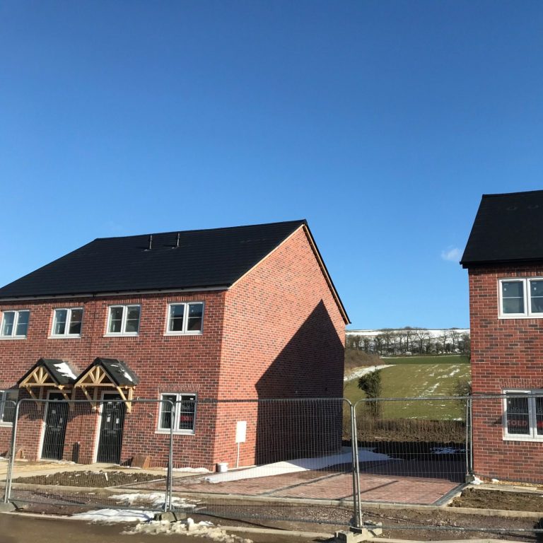 Newly constructed modern homes with gray Envirotile roofing, showcasing a uniform, eco-friendly tile at a residential development site
